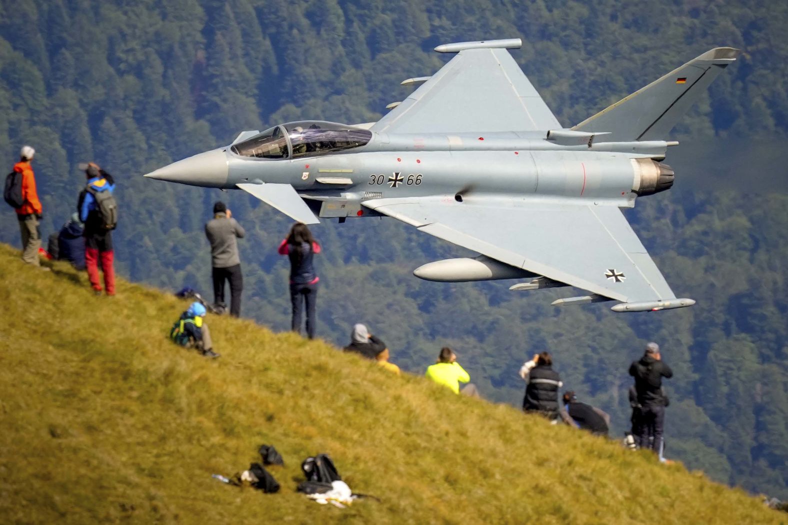 A German Air Force plane flies past people on top of a mountain during an aviation show in Bușteni, Romania, on Tuesday, August 26.