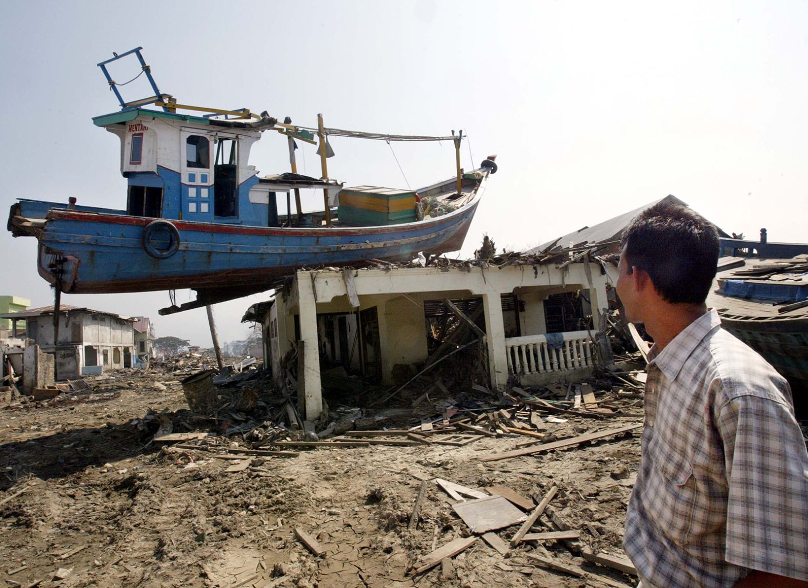 A man examines a boat perched on top of a house in Banda Aceh, Indonesia.