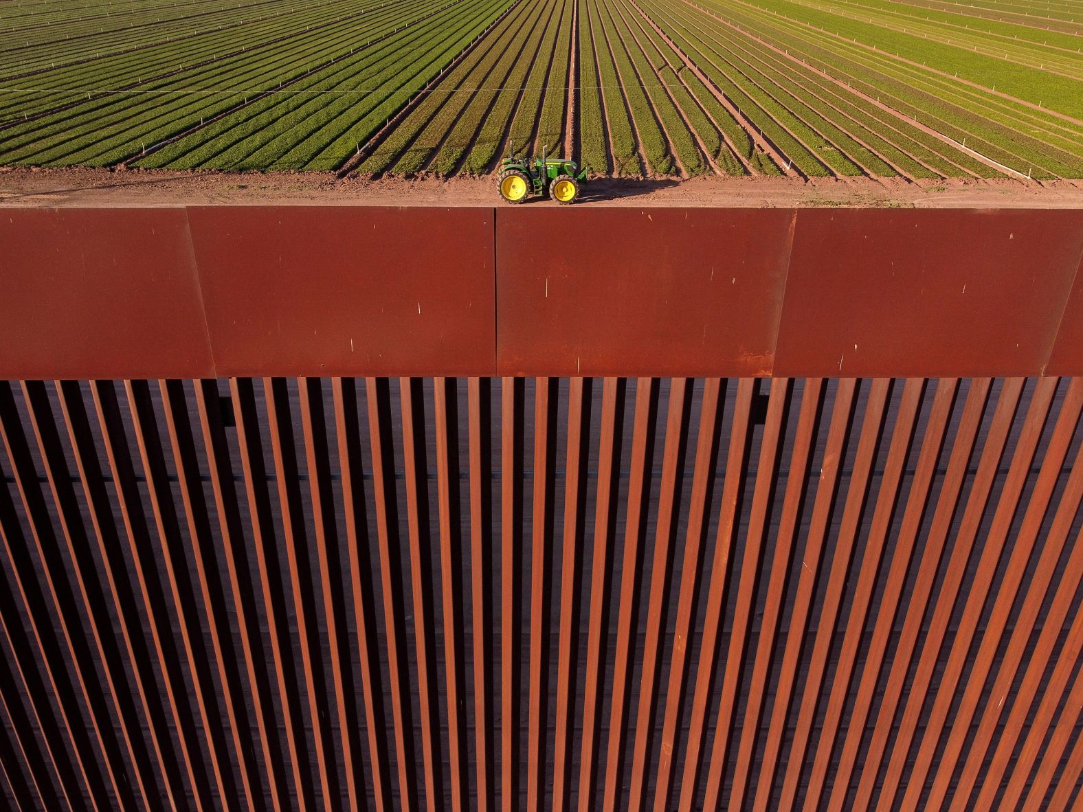 A tractor sits on a field in Calexico, California, behind a wall on the US-Mexico border on Tuesday, January 14.