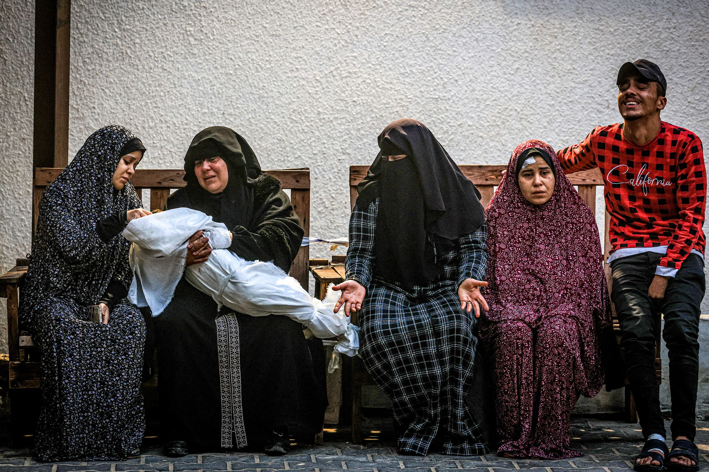 A woman holds the body of a baby as others mourn at the Najar hospital in Rafah, Gaza, on December 14.