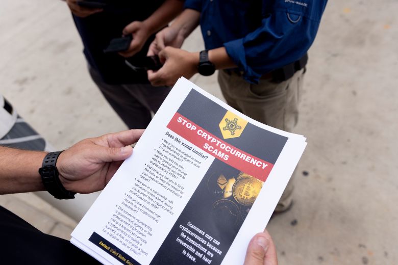 A Secret Service agent holds a warning about crypto ATM scams.