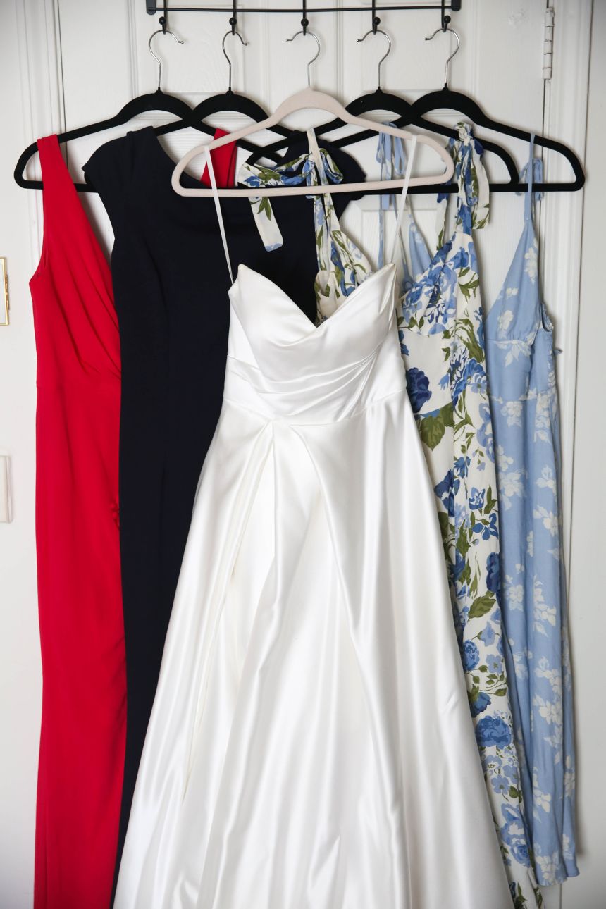Madeline Holcombe’s wedding dress hangs next to bridesmaids dresses that she has worn to other weddings.