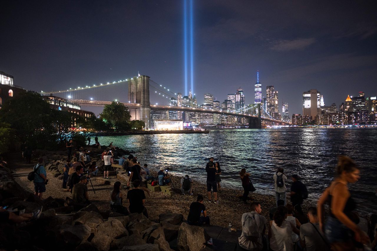 People on the shore watch The Tribute in Light shining into the sky over Manhattan's skyline on September 11, 2019.