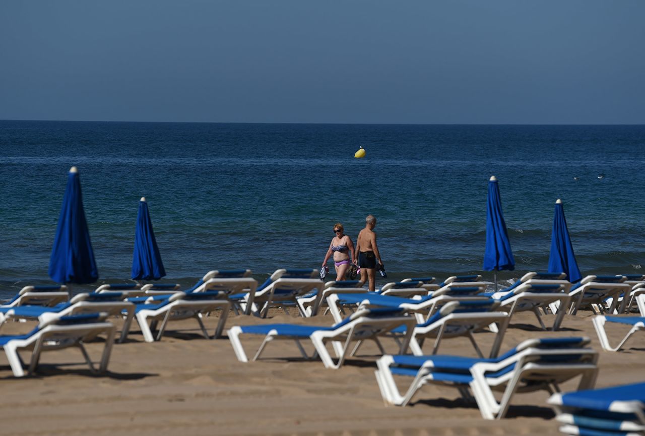 People walk past empty chairs at the beach Benidorm, Spain, on June 15.