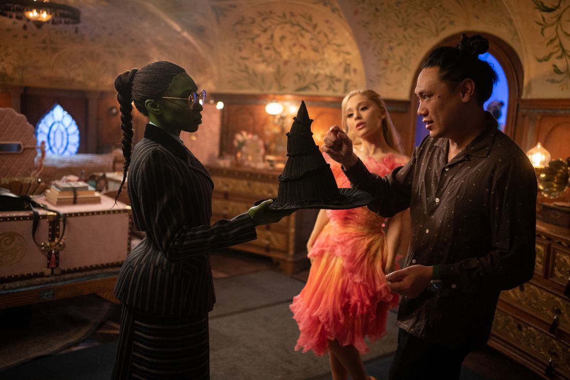 Cynthia Erivo (as Elphaba) and Ariana Grande (as Glinda) with Director Jon M. Chu on the set of "Wicked."