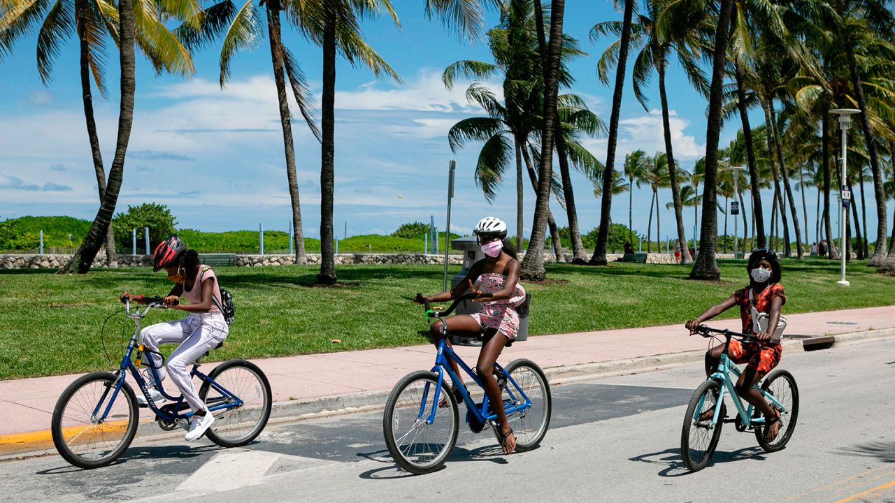 People wearing facemasks ride bicycles on Ocean Drive in Miami Beach, Florida on June 16.