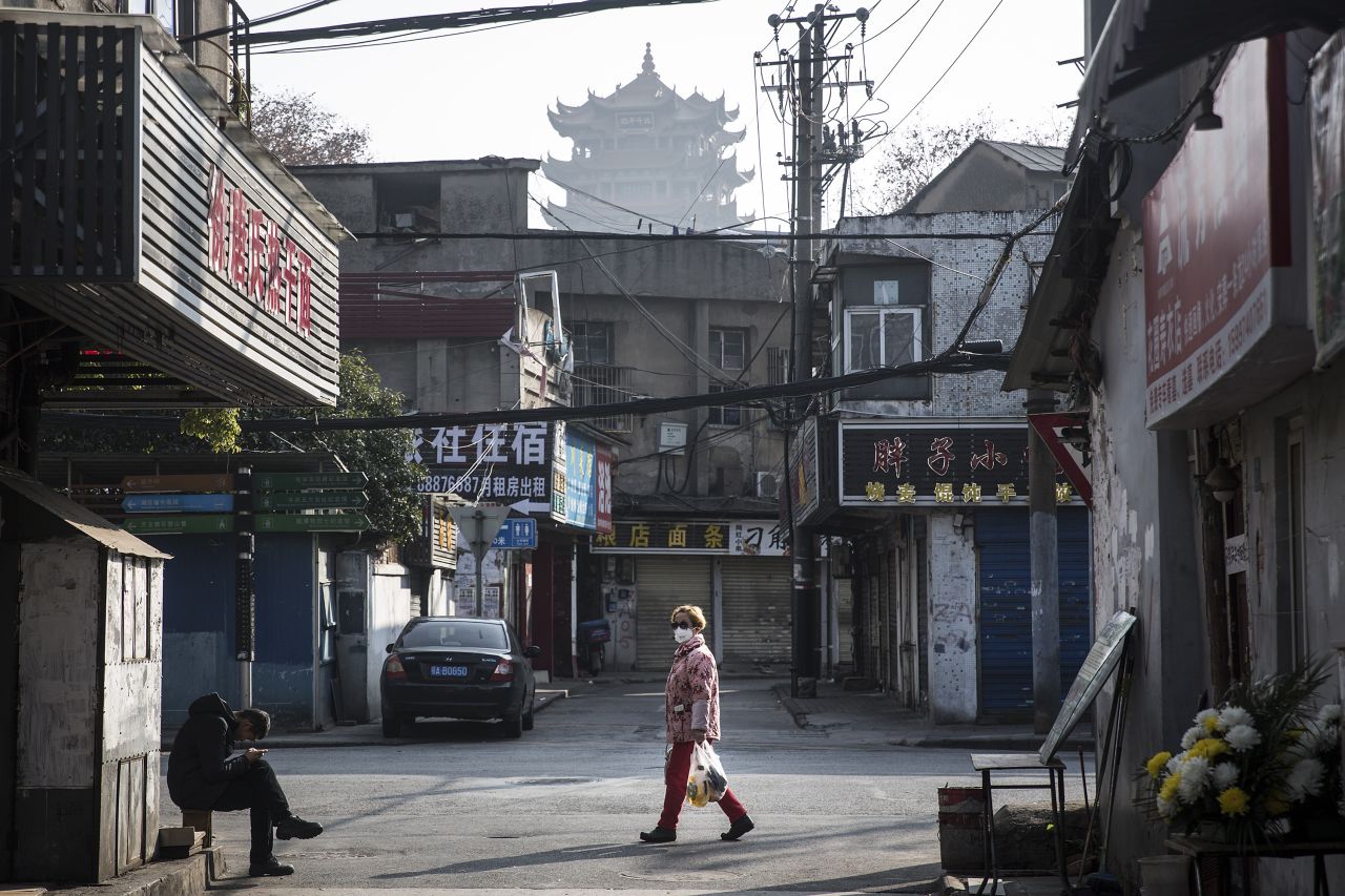 ?A woman wears a face mask as a man sits by the roadside on Friday in Wuhan, China.