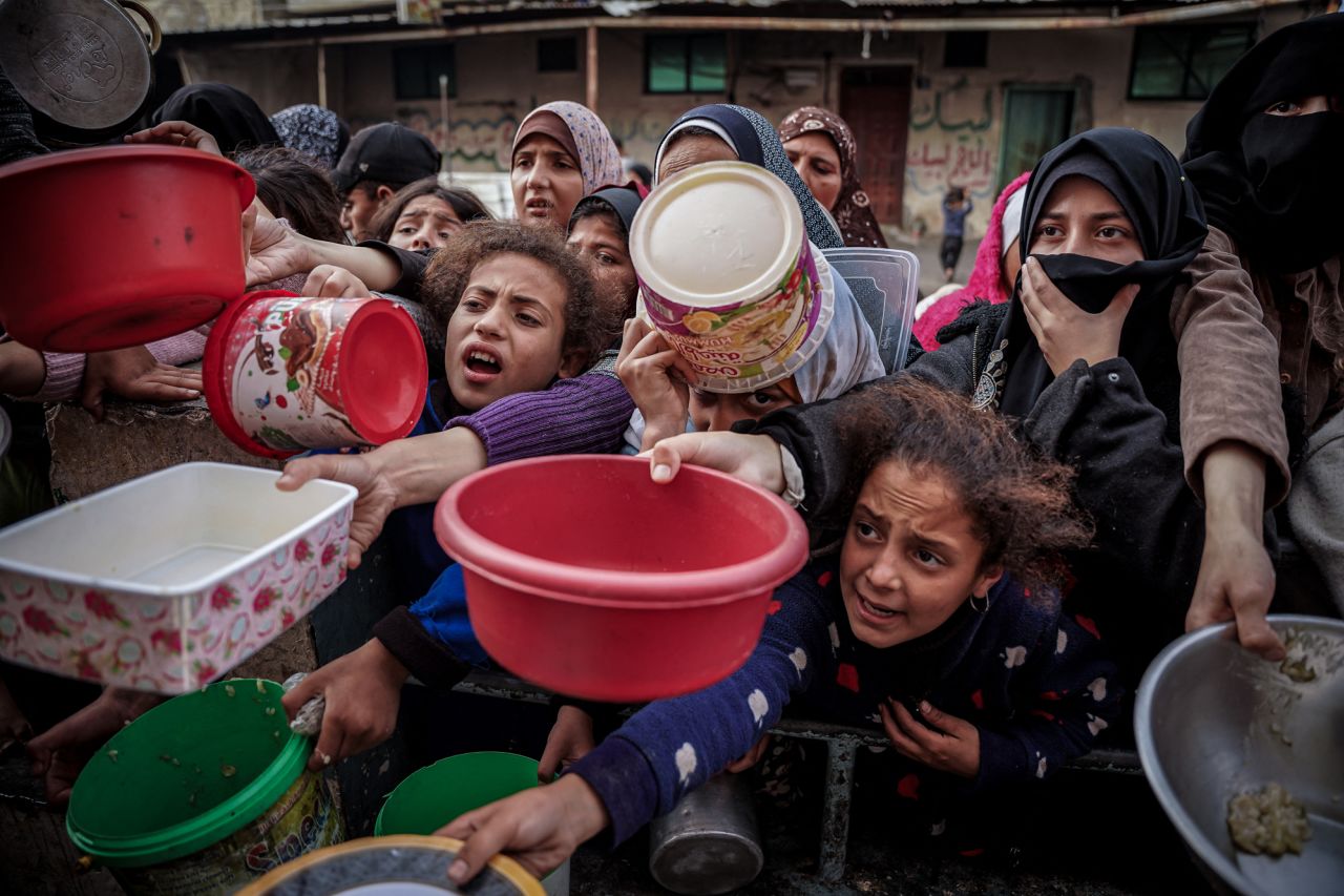 Palestinians wait to collect food at a donation site in a refugee camp in Rafah, southern Gaza, on December 23, 2023.
