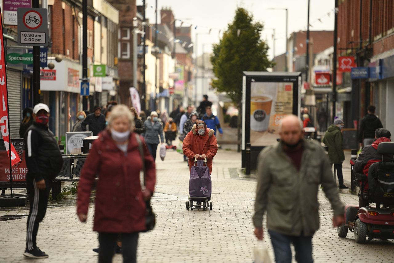 People wearing masks because the novel coronavirus pandemic walk in the high street in Leigh, Greater Manchester, northwest England on October 22.