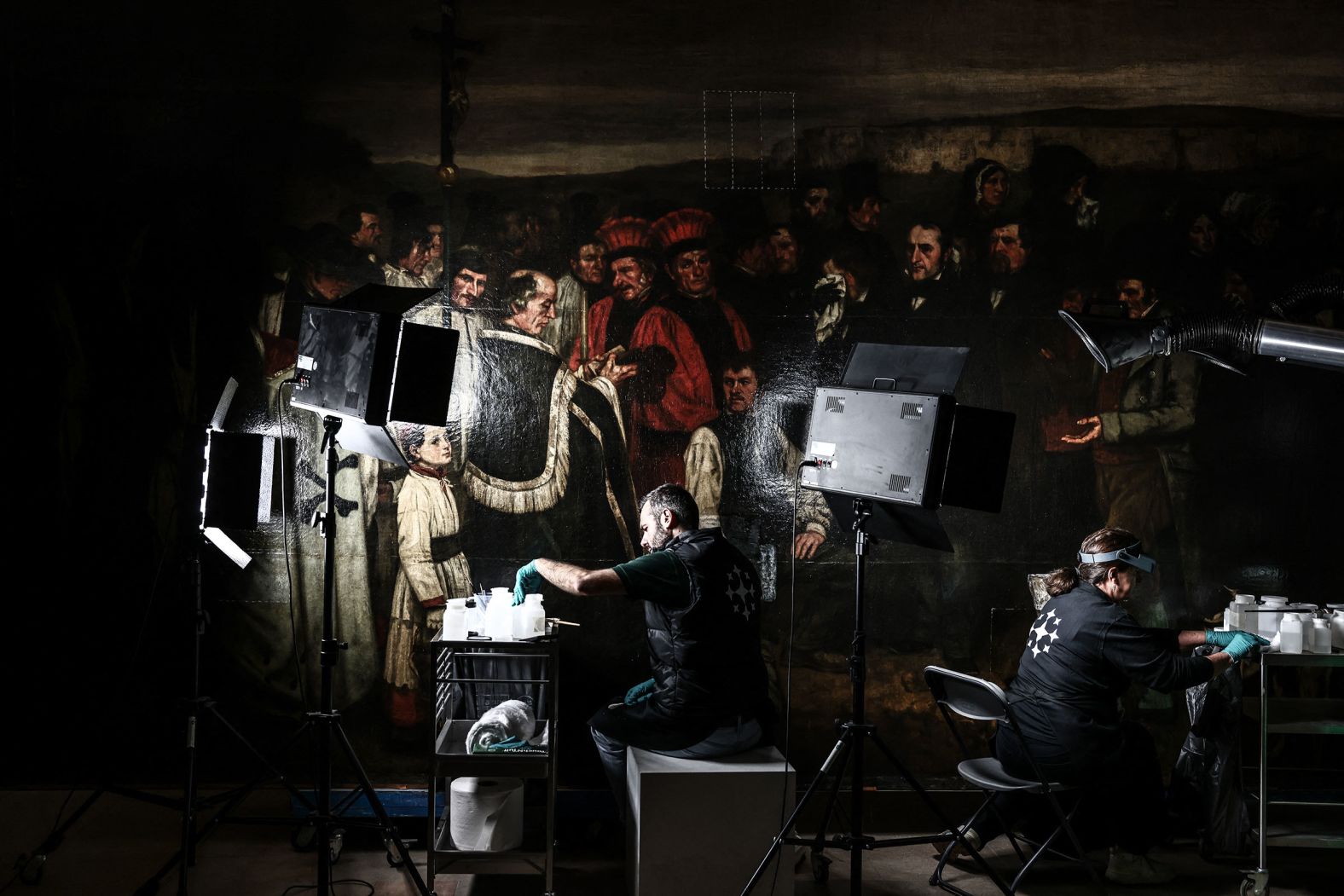 Art restorers work on Gustave Courbet's painting "A Burial at Ornans" at the Orsay Museum in Paris on Wednesday, May 7. The painting had not undergone any significant restoration for at least half a century.