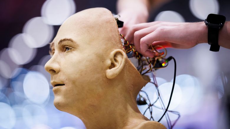 TOPSHOT - CORRECTION / A man works on the electronics of Jules, a humanoid robot from Hanson Robotics that uses artificial intelligence, at a stand during the International Telecommunication Union (ITU) AI for Good Global Summit in Geneva on July 8, 2025. (Photo by Valentin FLAURAUD / AFP) / "The erroneous mention[s] appearing in the metadata of this photo by FABRICE COFFRINI has been modified in AFP systems in the following manner: [Valentin Flauraud] instead of [Fabrice Coffrini]. Please immediately remove the erroneous mention[s] from all your online services and delete it (them) from your servers. If you have been authorized by AFP to distribute it (them) to third parties, please ensure that the same actions are carried out by them. Failure to promptly comply with these instructions will entail liability on your part for any continued or post notification usage. Therefore we thank you very much for all your attention and prompt action. We are sorry for the inconvenience this notification may cause and remain at your disposal for any further information you may require." (Photo by VALENTIN FLAURAUD/AFP via Getty Images)          
