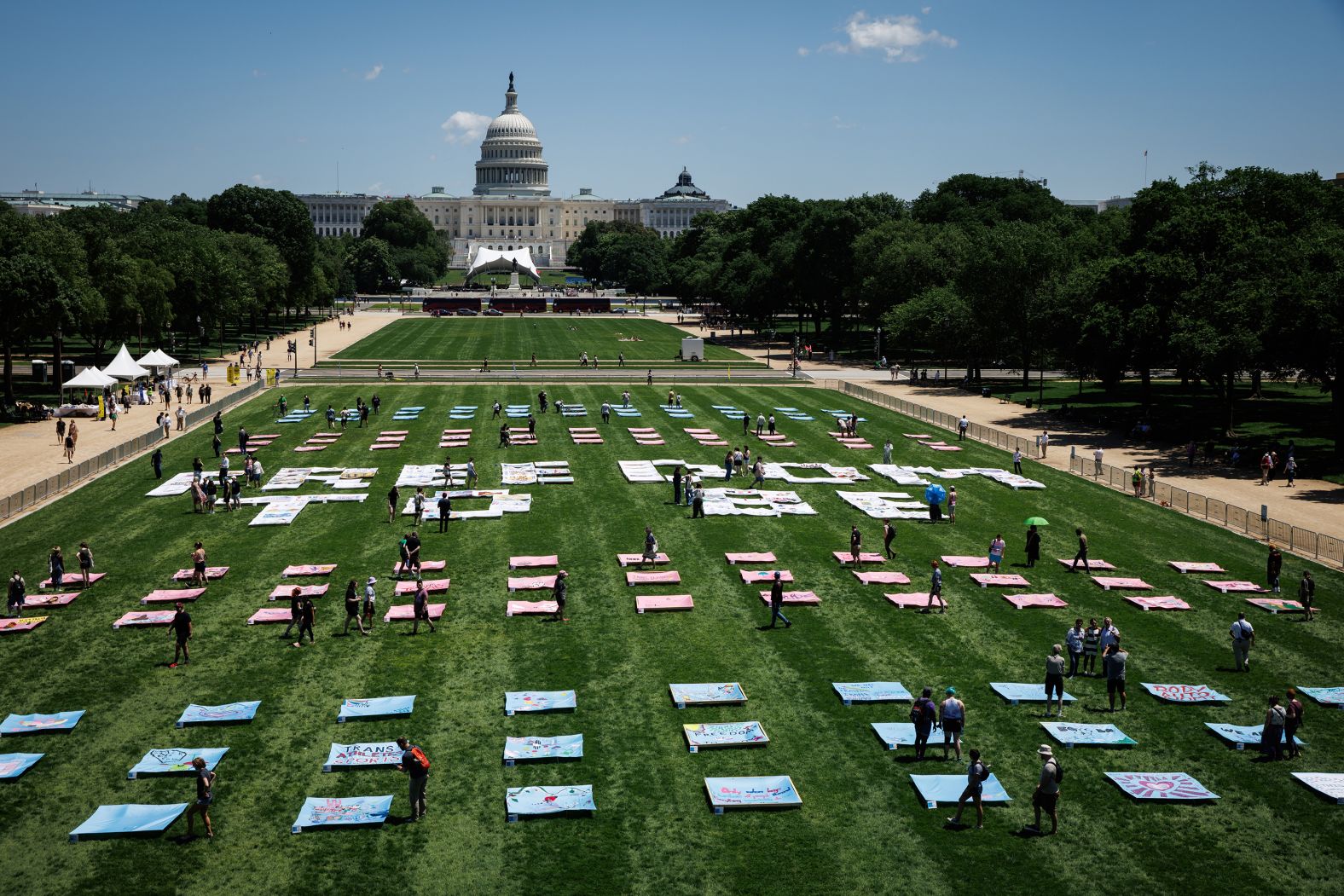 People view sections of the <a href="https://www.cnn.com/2025/03/31/us/gallery/trans-visibility-freedom-to-be-quilt">"Freedom to Be" quilt</a> on the National Mall in Washington, DC, on Saturday, May 17. The art installation, made by transgender and nonbinary Americans across the country, was unveiled in conjunction with WorldPride celebrations.