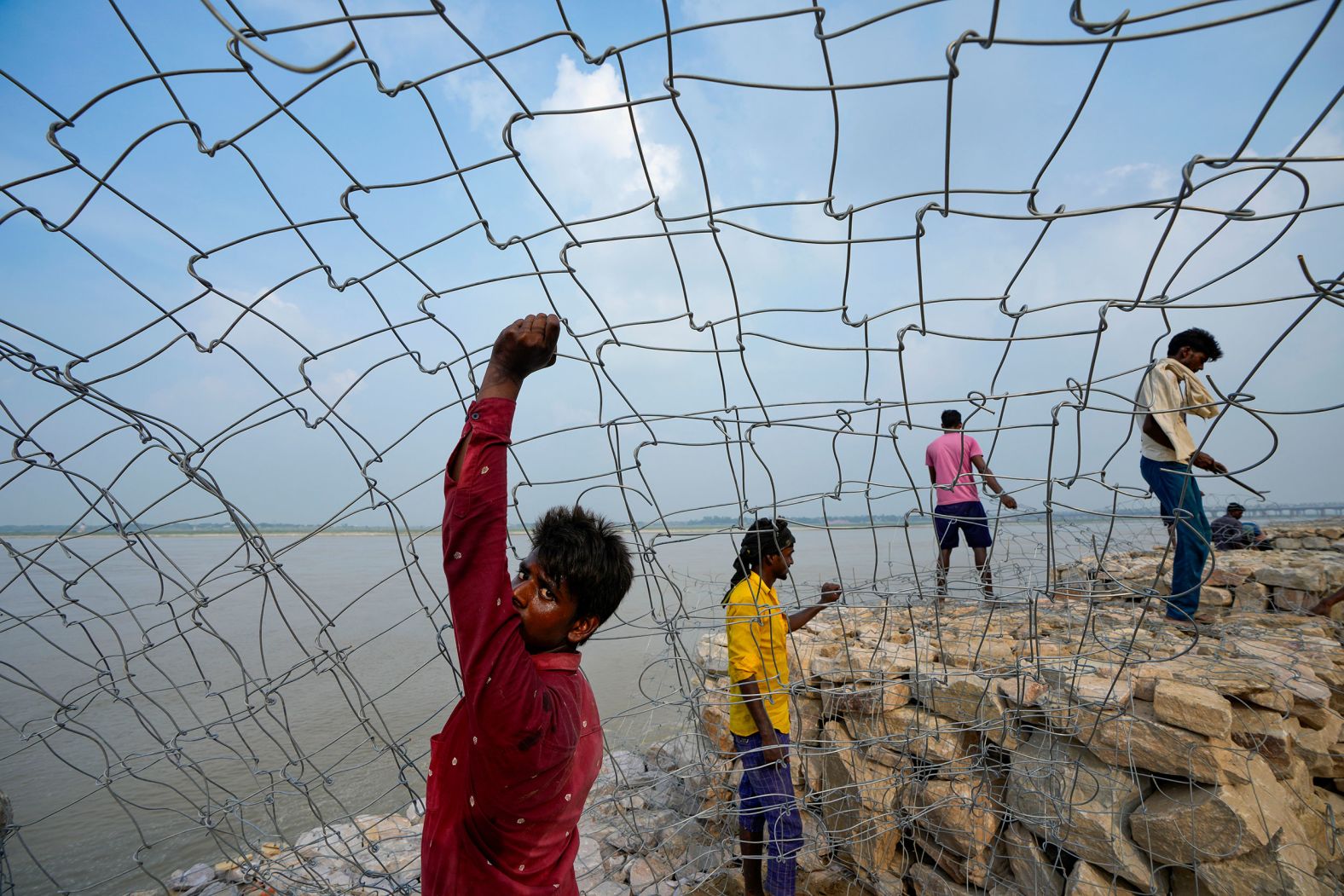 Laborers in Prayagraj, India, work on a road construction site adjacent to the Ganges River on Friday, July 26.