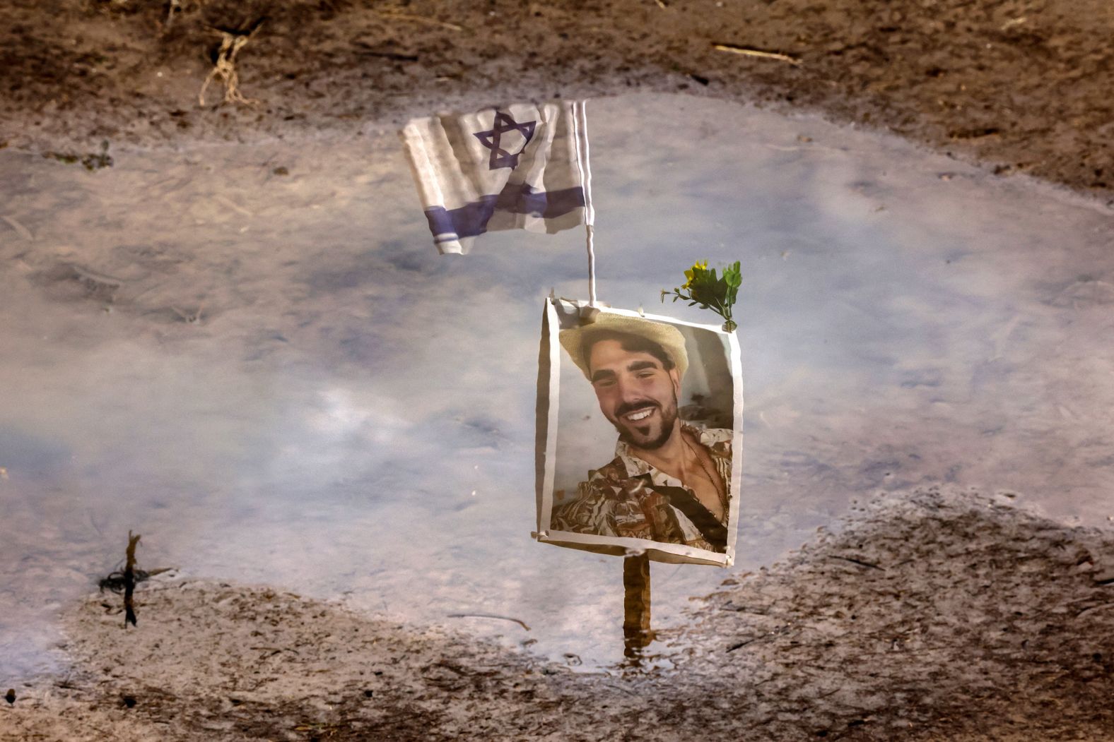 A person’s portrait is reflected in water January 11 at the site of the music festival in southern Israel that was overrun by Hamas militants in October. The site today is filled with Israeli flags and pictures of those who have been killed or taken captive by Hamas.