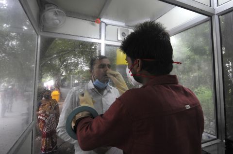 A health worker in an enclosed kiosk collects a swab sample for a coronavirus test, at the Government District Hospital, on August 28, in Noida, India. 