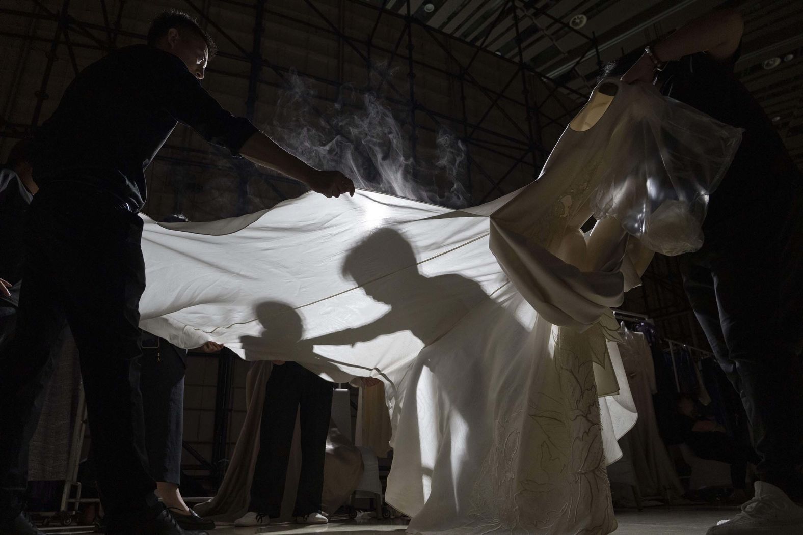 Workers steam press gowns backstage before a Misuity fashion show held on the outskirts of Beijing on Friday, September 5.