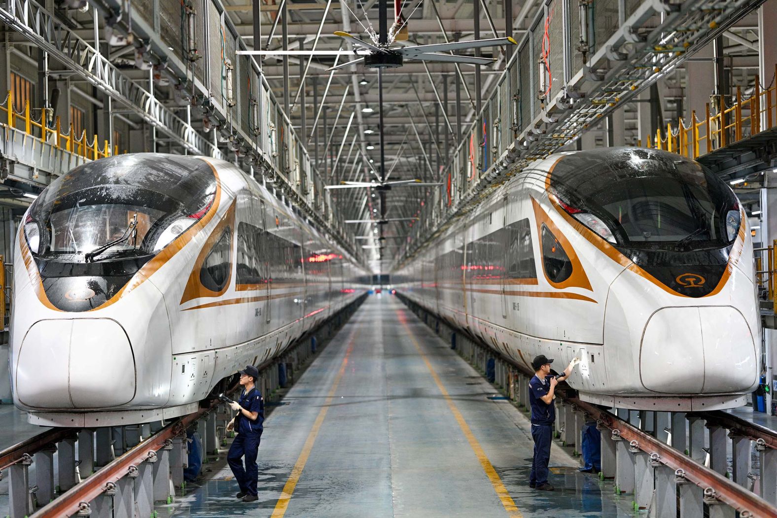 Ground mechanics inspect high-speed trains in the maintenance workshop of the Nanjing South EMU Operation Station in Nanjing City, China, on Wednesday, October 1.