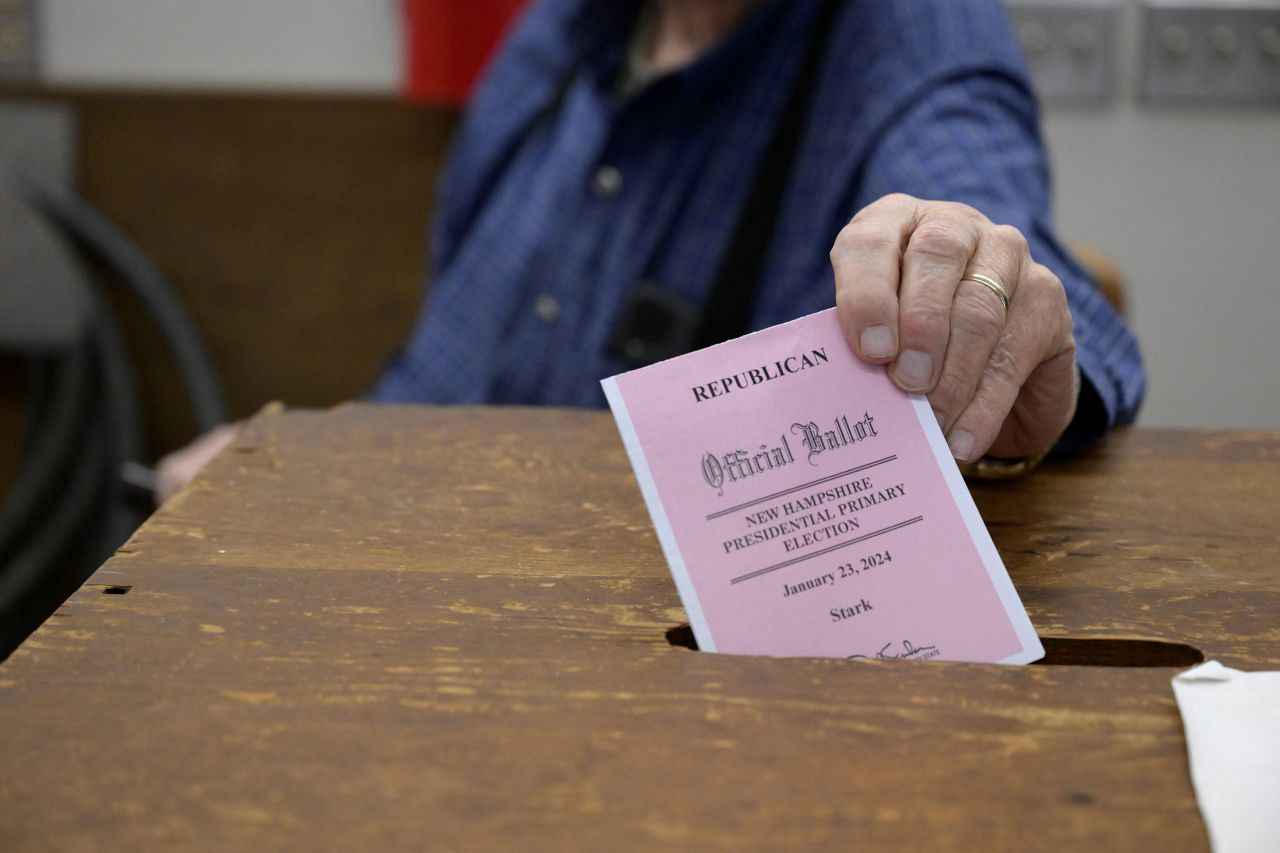 A moderator drops a ballot into a voting box in Stark, New Hampshire.