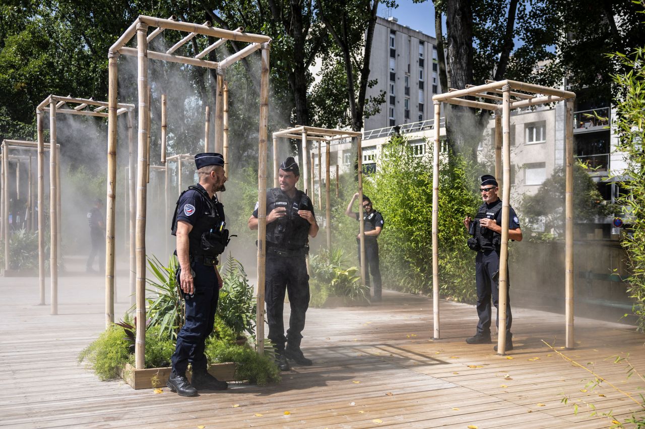 Police officers cool off under misters in Paris on Tuesday.
