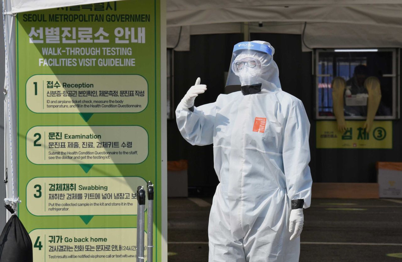 A Seoul city official guides visitors at a walk-thru coronavirus testing station in Seoul on April 3.