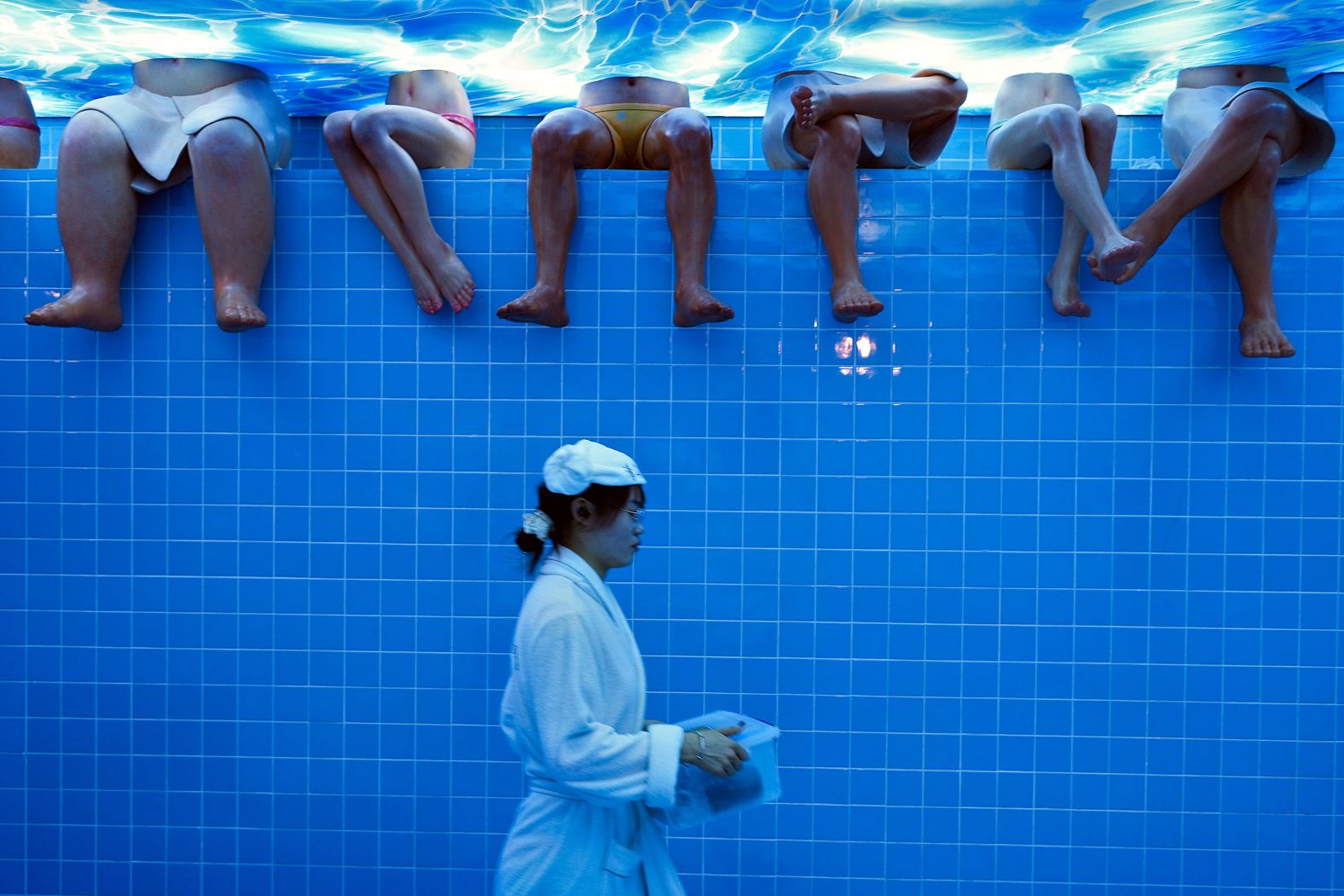 A waitress wearing a bathrobe walks by mannequins at a Beijing restaurant set up to look like a bathhouse on Sunday, August 11.