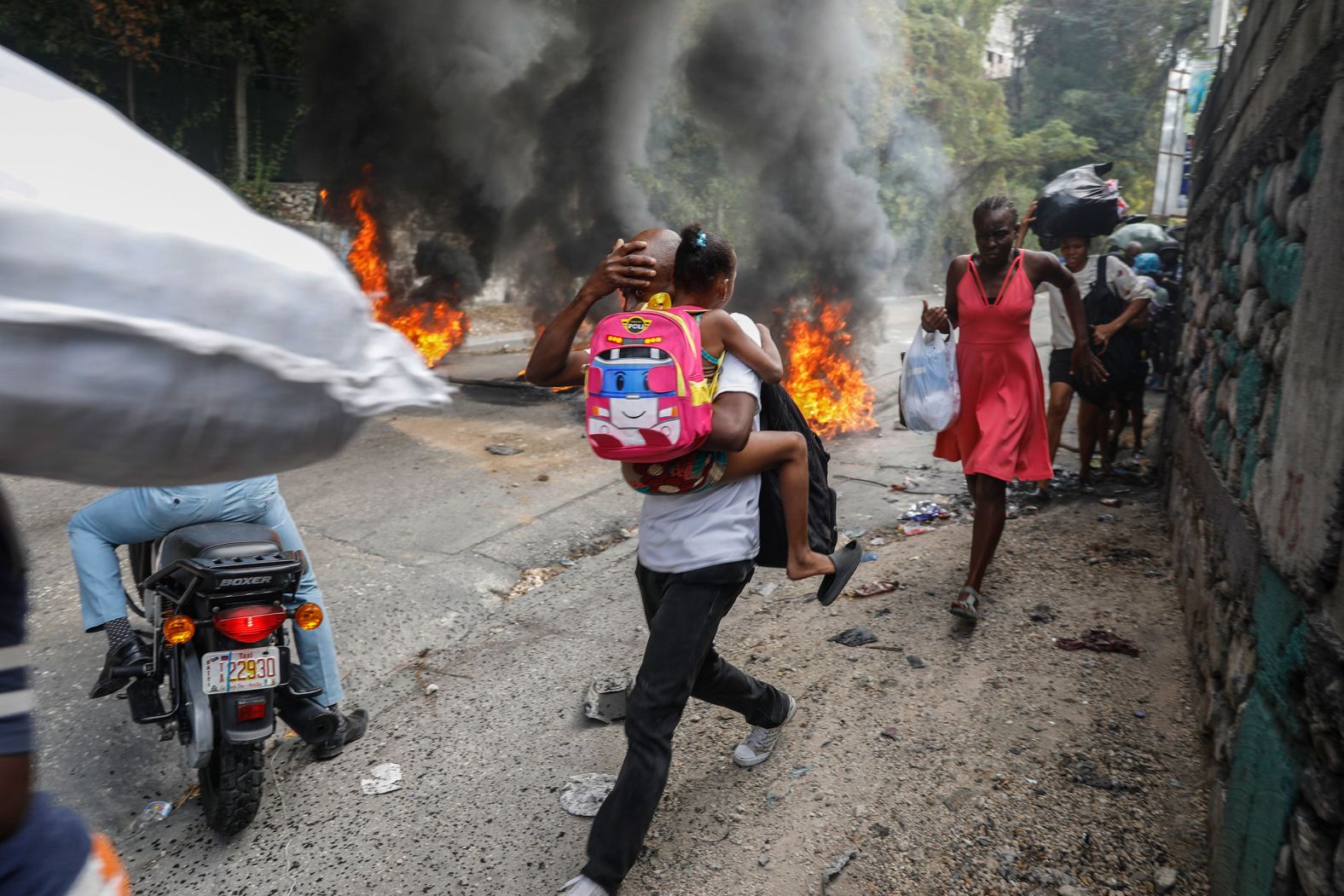 People walk past burning tires during a protest against Haitian Prime Minister Ariel Henry in Port-au-Prince, Haiti, on Monday, February 5. The country has seen <a href="index.php?page=&url=https%3A%2F%2Fwww.cnn.com%2F2023%2F08%2F01%2Famericas%2Fhaiti-violence-explained-intl%2Findex.html">deepening unrest</a> since the 2021 assassination of President Jovenel Moïse.