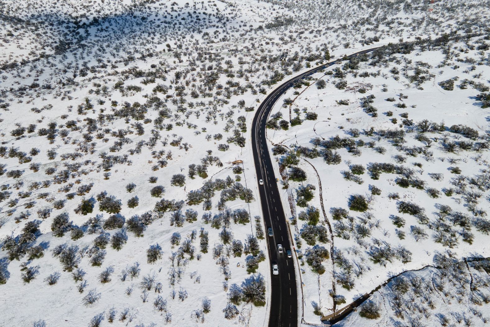 Cars are driven along a snow-covered road in Santiago, Chile, on Tuesday, August 6.
