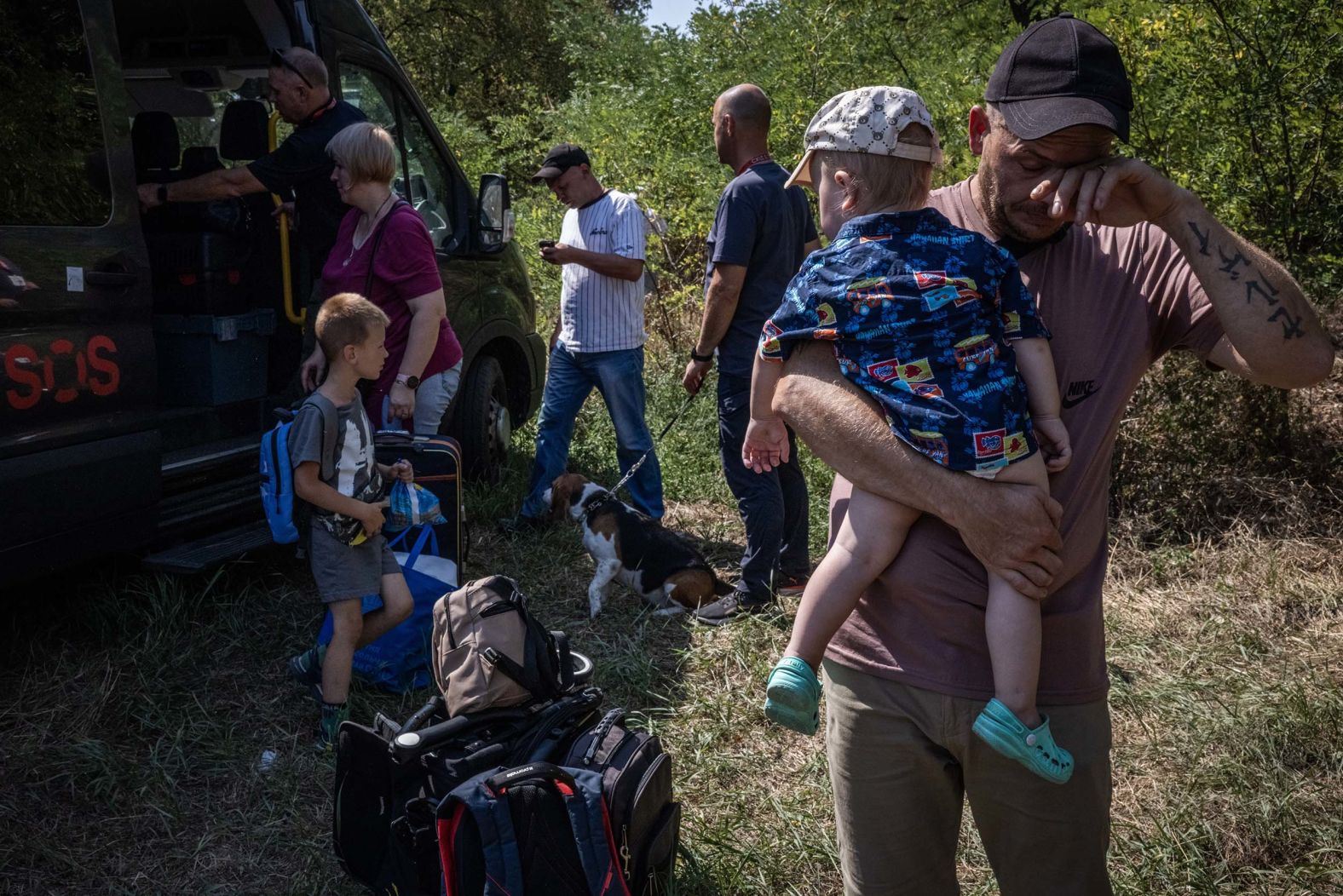 Serhii Nakhalenko cries as he holds his youngest son, Danylo, as he and his wife, Natalia, arrive with their other children at an evacuation transit area in Ukraine’s Donetsk region on Monday, August 18.