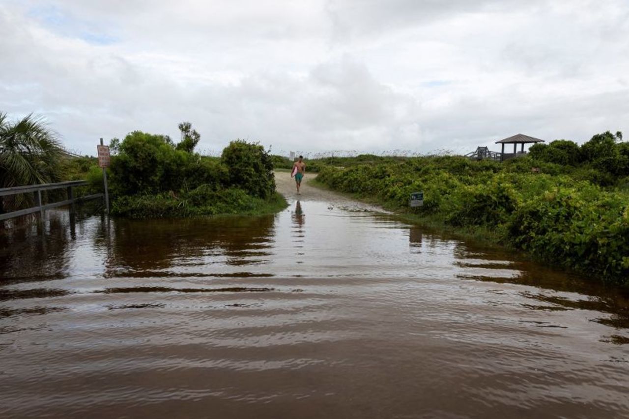 A man walks Tuesday through a flooded entrance to the beach in Isle of Palms, South Carolina, as Tropical Storm Debby moves off Georgia to the North Atlantic. 