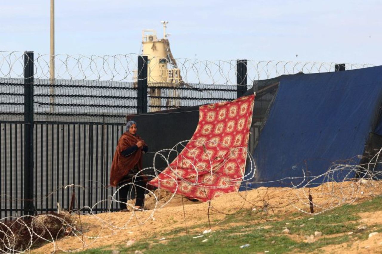 A displaced Palestinian woman walks near the border fence between Gaza and Egypt on February 16, in Rafah, Gaza.