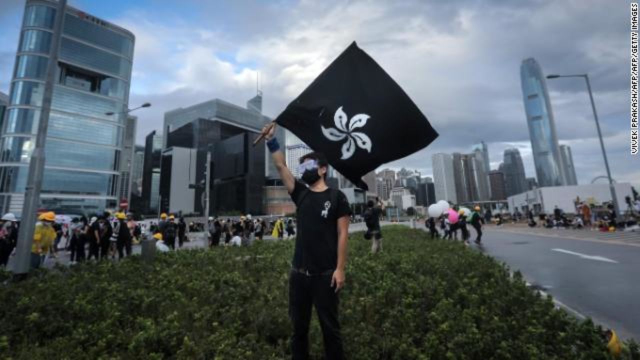 A protester waves a "black bauhinia" flag as others set up barricades outside the Legislative Council in Hong Kong before the flag-raising ceremony on July 1, 2019.?