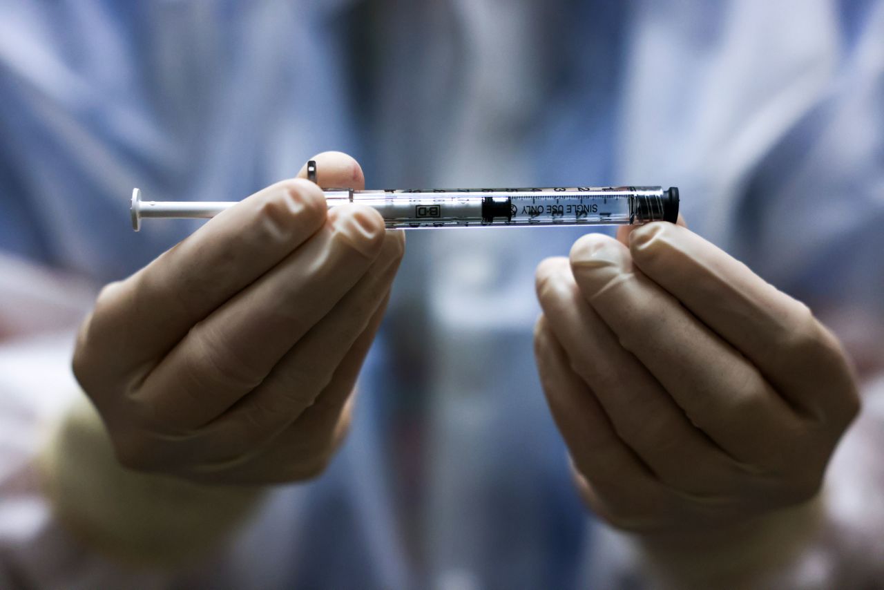 An?investigational pharmacy technician holds a dose of the Johnson & Johnson Covid-19 vaccine before it is administered in a clinical trial in Aurora, Colorado, on December 15, 2020.