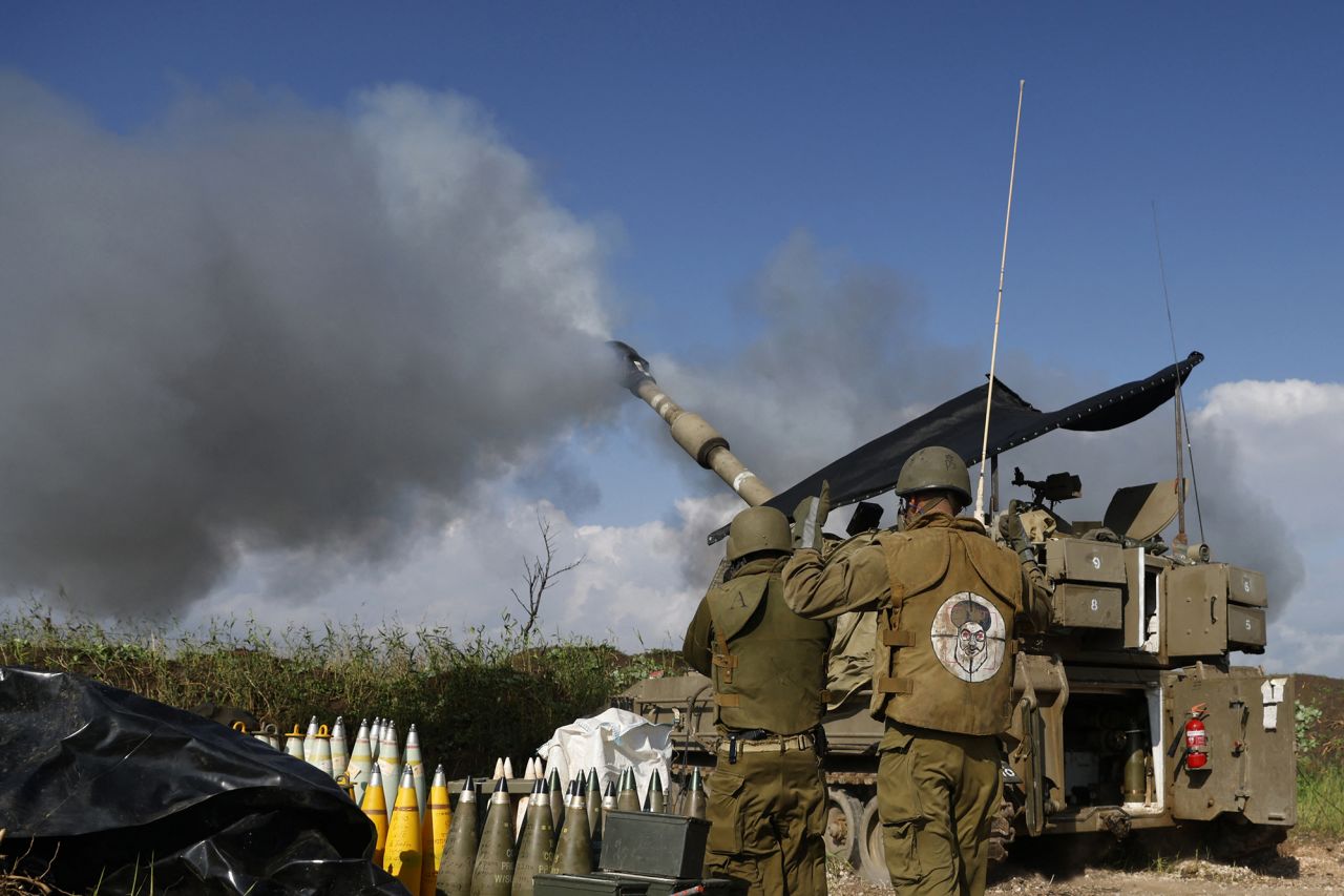 Israeli soldiers stand in front of a tank in Upper Galilee in northern Israel, as an artillery unit shells southern Lebanon on January 4.