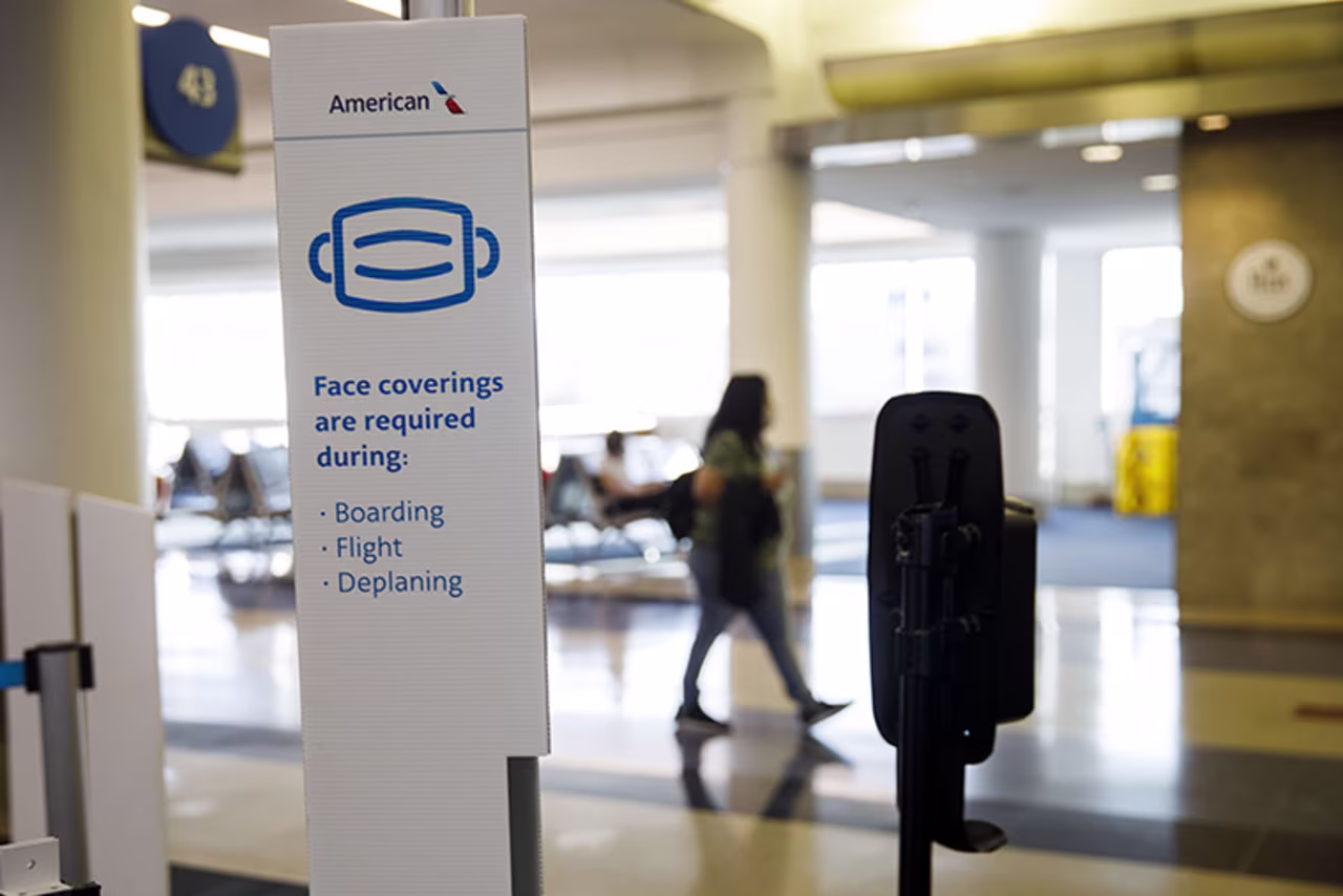 A sign reminds travelers to wear face coverings displayed at an American Airlines Group Inc. boarding gate at Los Angeles International Airport in Los Angeles, California, U.S., on Thursday, Oct. 1, 2020. 