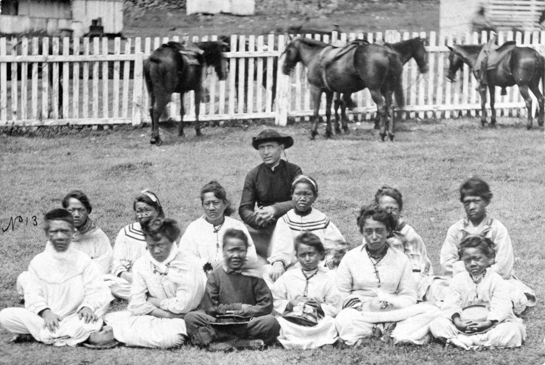 Father Damien is pictured with the Kalawao Girls Choir, circa 1878. Kalawao is a settlement on the Kalaupapa Peninsula.