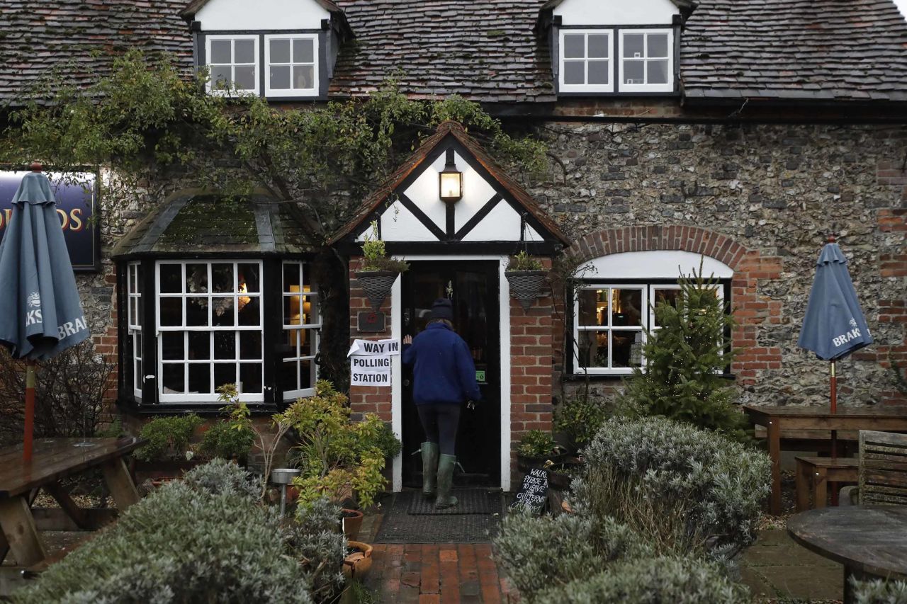 A woman arrives to vote at a polling station in the Fox & Hounds pub in the hamlet of Christmas Common, England. Photo: Matt Dunham/AP