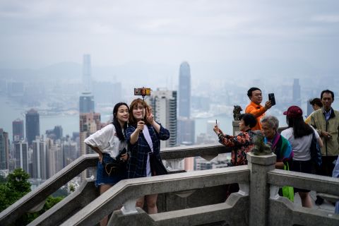 Tourists take selfies from Victoria Peak in front of a view of residential and commercial buildings in Kowloon (background) and Hong Kong Island on May 3.