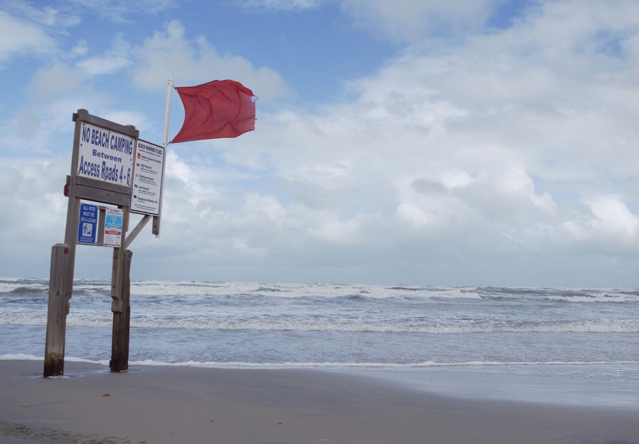 A red warning flag whips in the wind along the shoreline near Bob Hall Pier on North Padre Island, an island along the coast of Texas, on Tuesday.