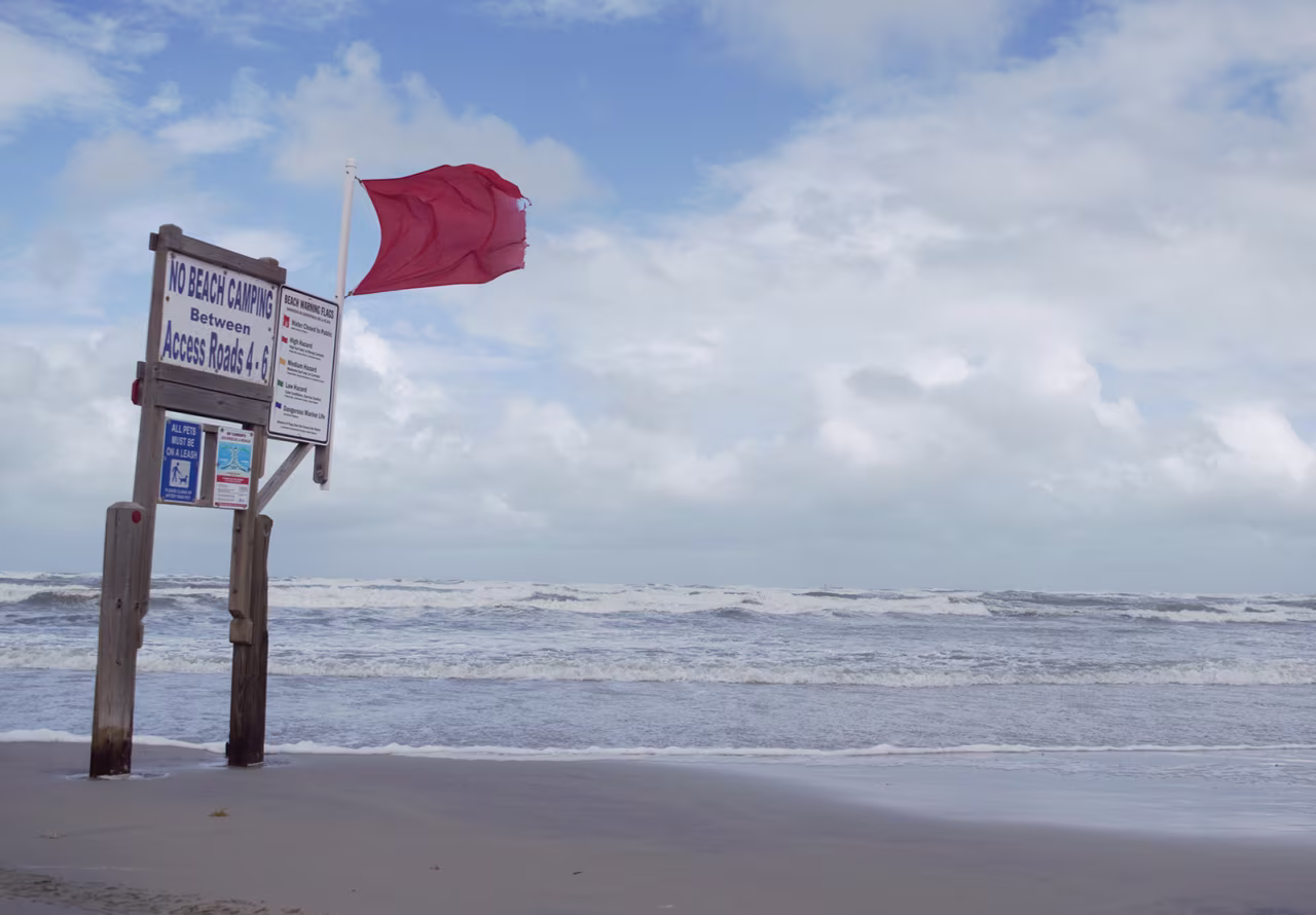 A red warning flag whips in the wind along the shoreline near Bob Hall Pier on North Padre Island, an island along the coast of Texas, on Tuesday.