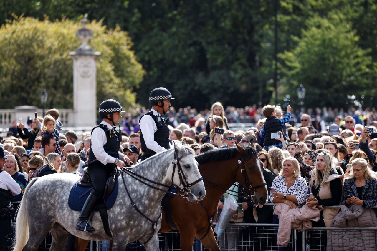 Police officers patrol on their horses as members of the public gather outside of Buckingham Palace on?Sunday.