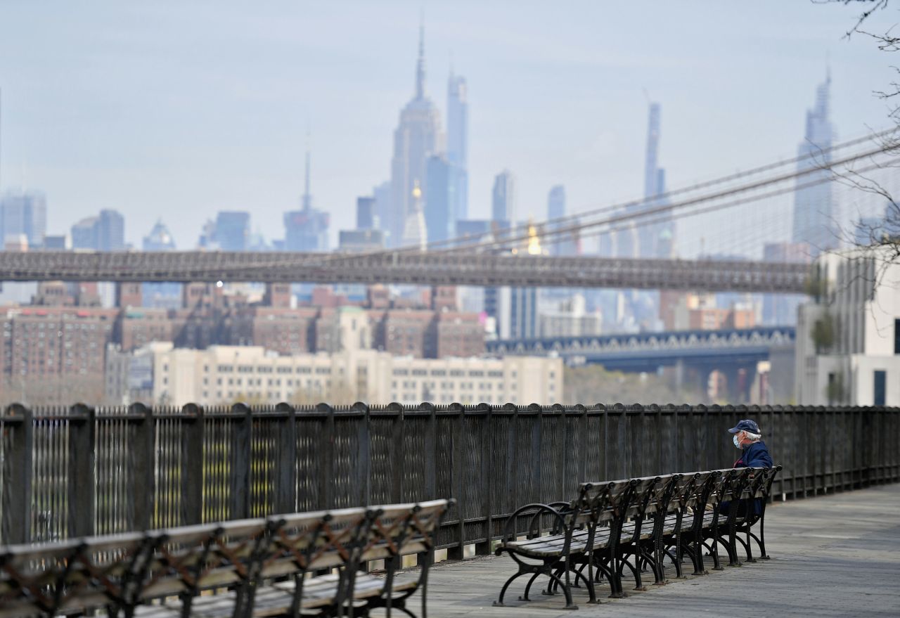 A man sits alone on a bench overlooking part of the Manhattan skyline amid the coronavirus pandemic on April 21 in Brooklyn, New York. 