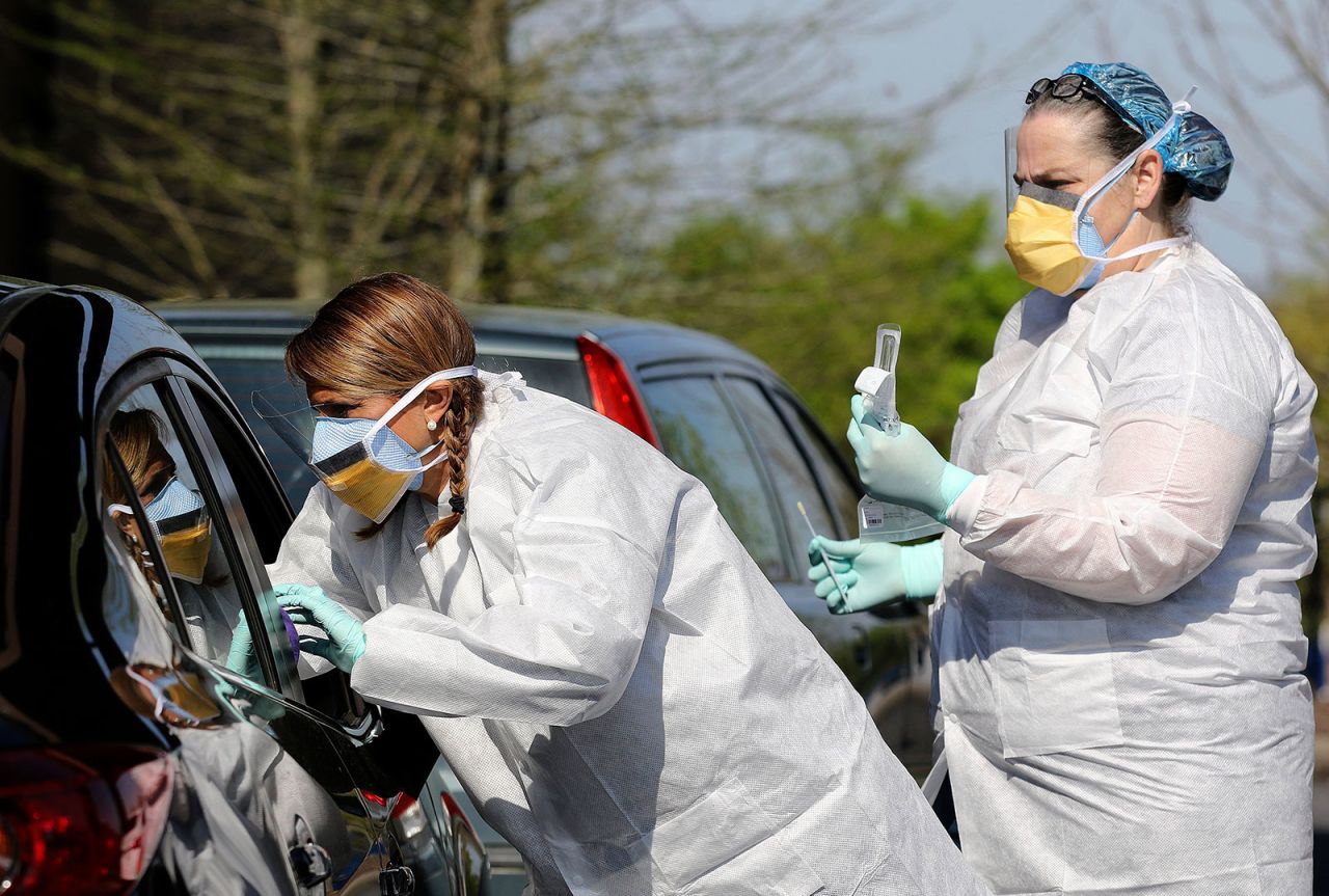 Nurse Mandy Stuckey reaches into a vehicle to administer a coronavirus test at a drive-through testing center in North Little Rock, Arkansas.