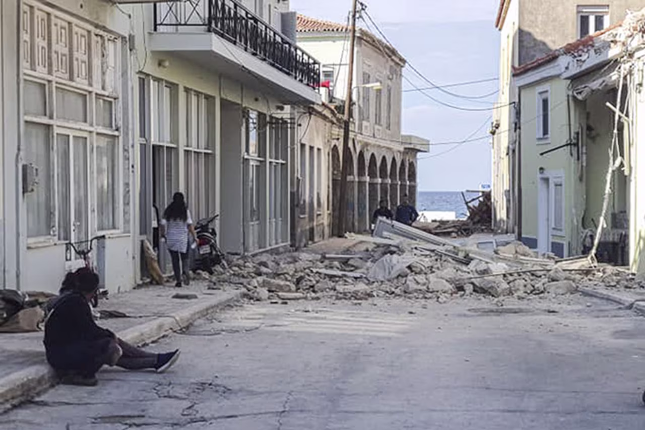 People walk past a destroyed house after an earthquake on the island of Samos on October 30, 2020