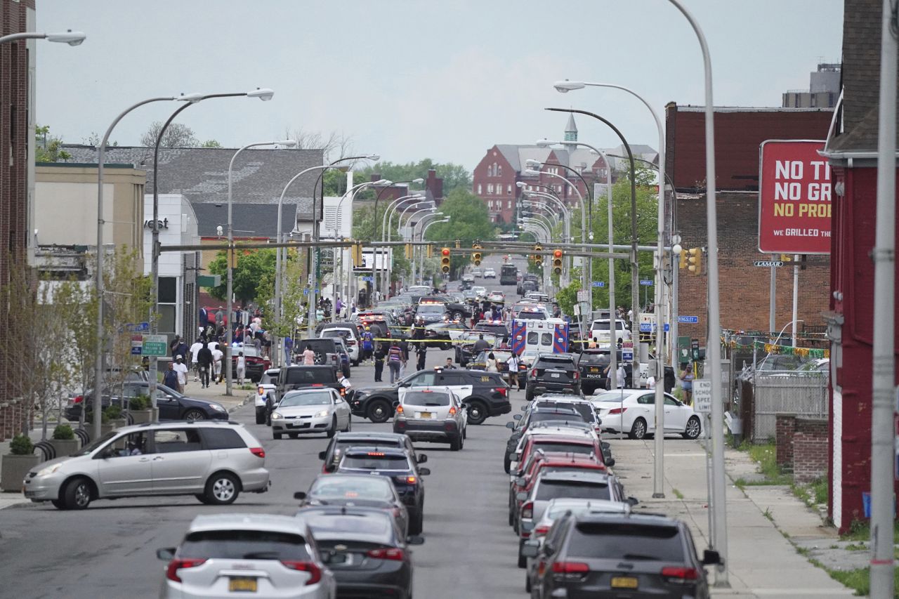 Police vehicles block off the street where at least 10 people were killed in a mass shooting at a Buffalo supermarket.