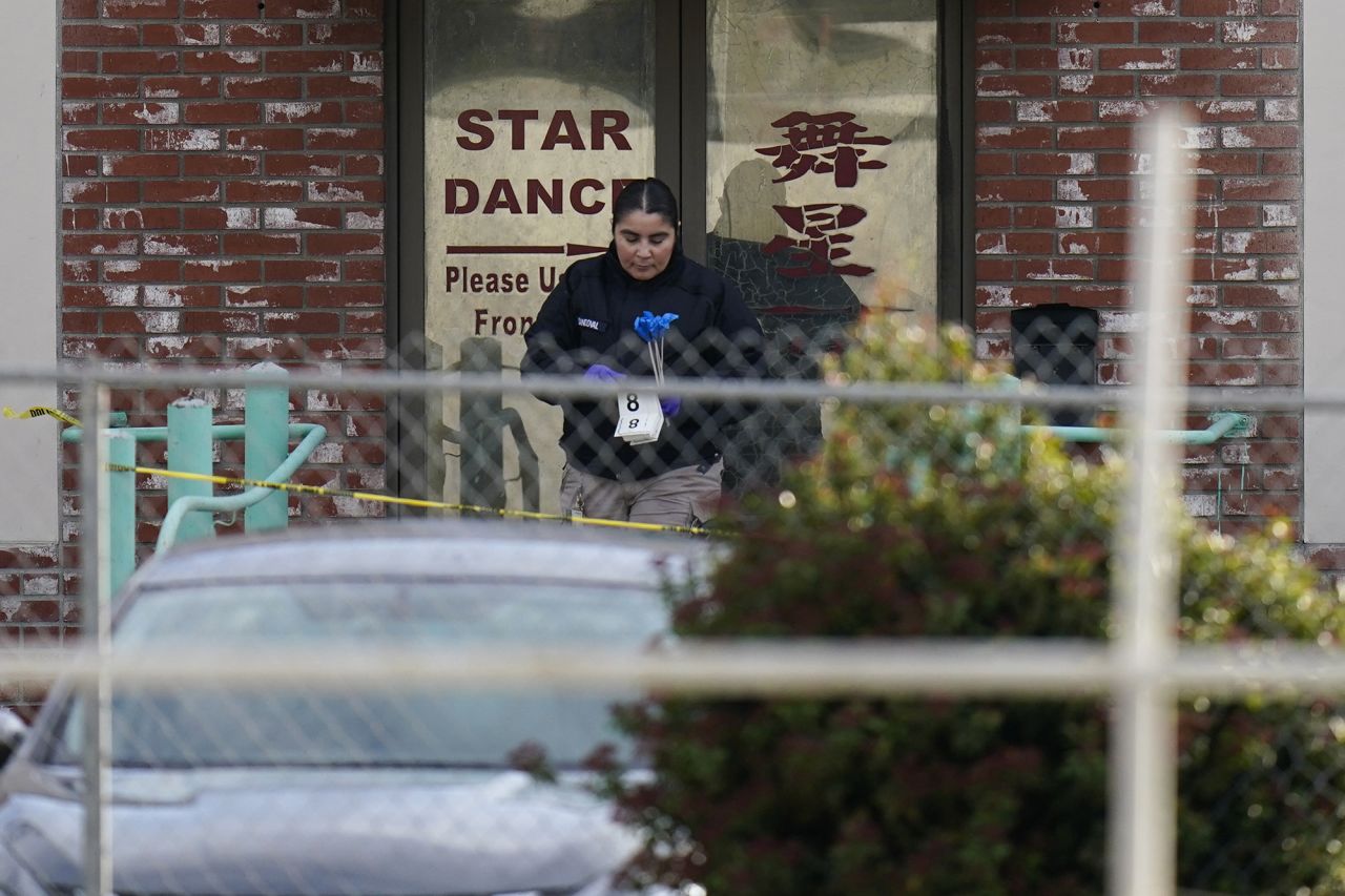 An investigator carries markers outside Star Ballroom Dance Studio.