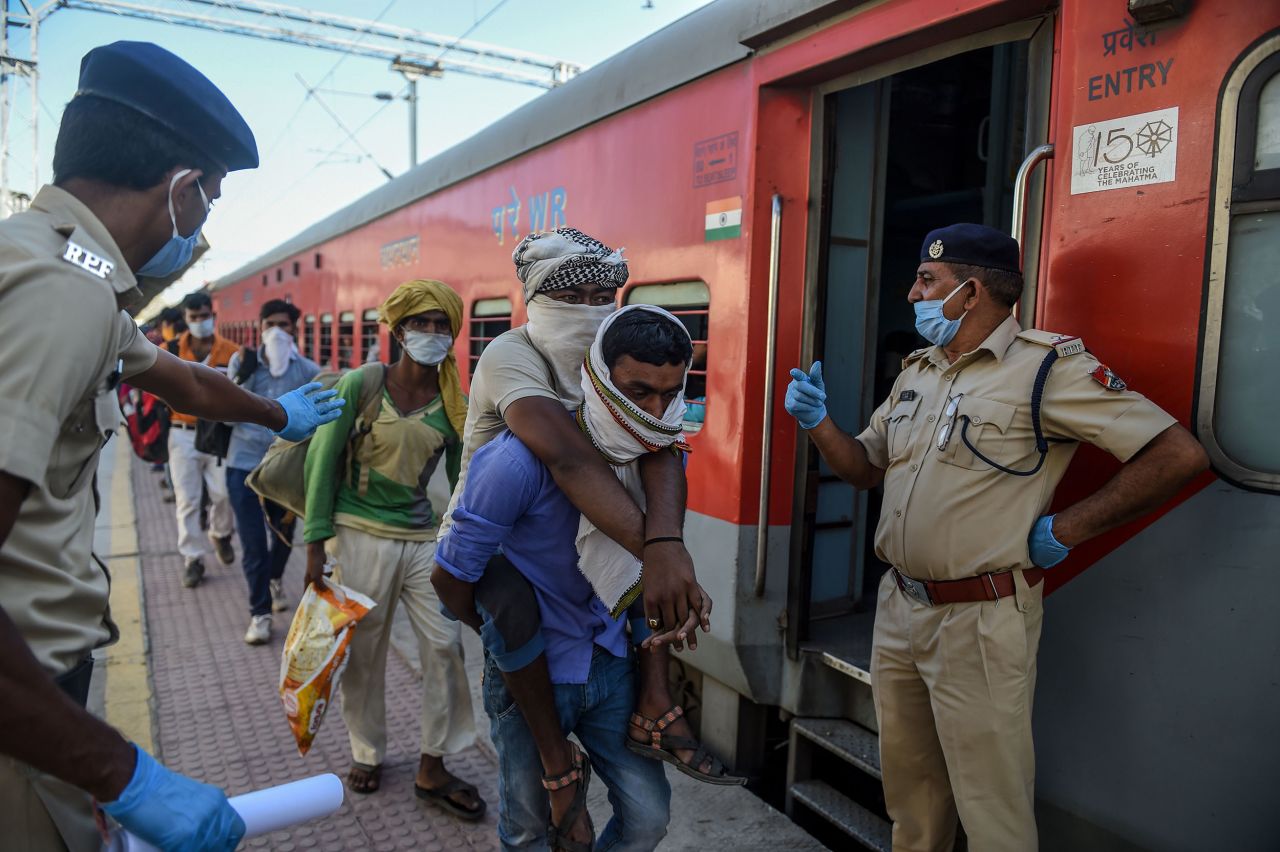 A migrant worker lifts his disabled brother, center, as they board a special train at Sabarmati Railway Station near Ahmedabad, India, on May 2.?