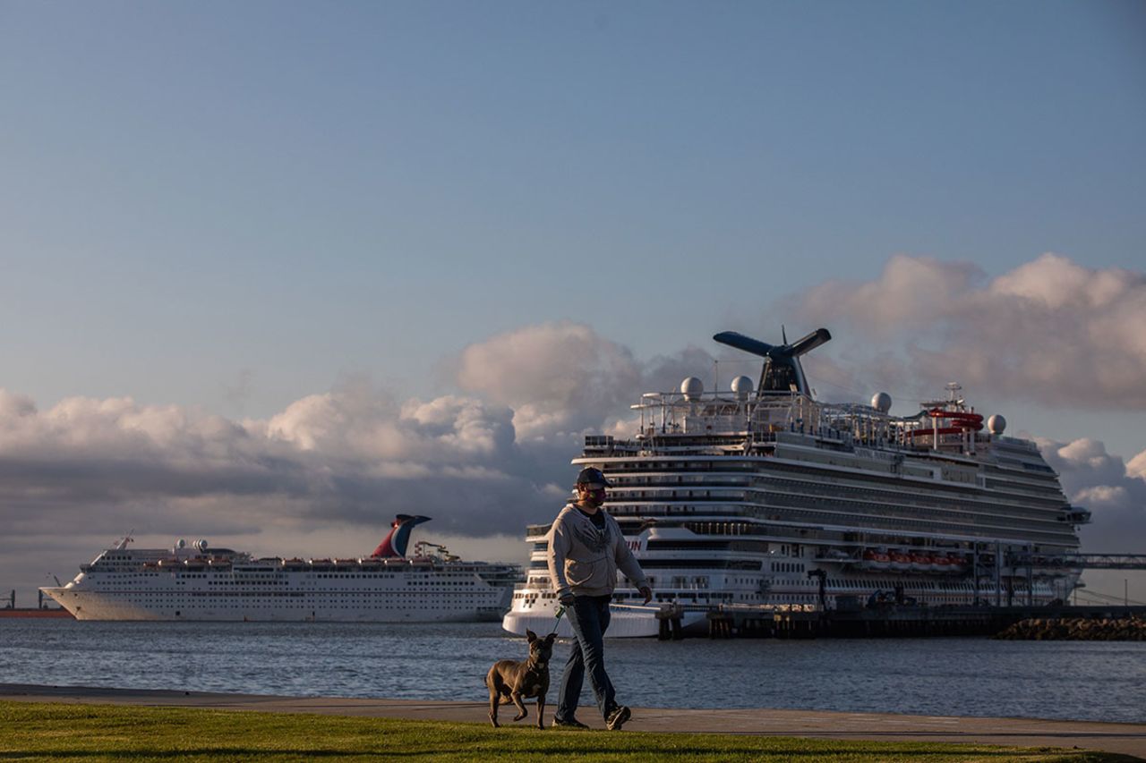 A man walks with his dog at the Marina Long Beach with cruise ships docked at the port due to a no-sail order in Long Beach, California on April 11.