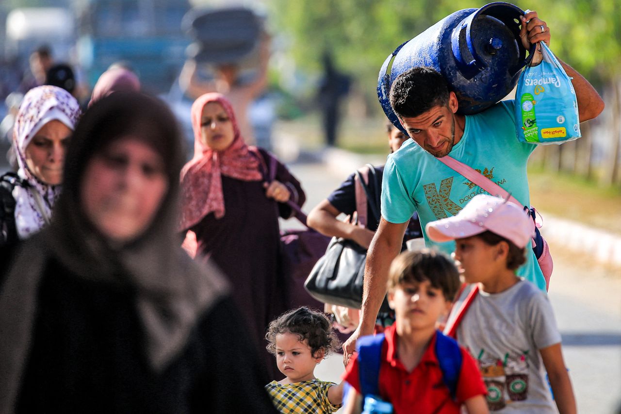 A man carries a cooking gas cylinder on his shoulder as he walks with other displaced people fleeing from the eastern parts of Deir el-Balah towards central Gaza on June 8.