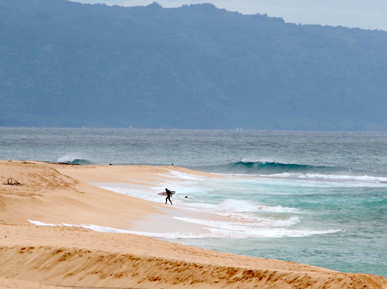 A surfer walks out of the ocean on Oahu's North Shore near Haleiwa, Hawaii, on Tuesday, March 31.