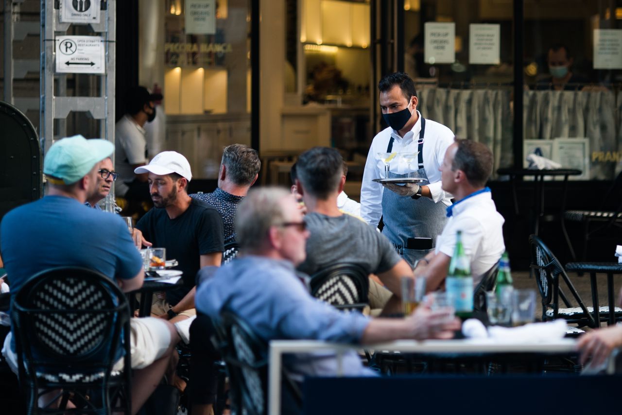 A waiter wearing a protective mask serves drinks outside a restaurant on July 21, 2020 in New York City. 